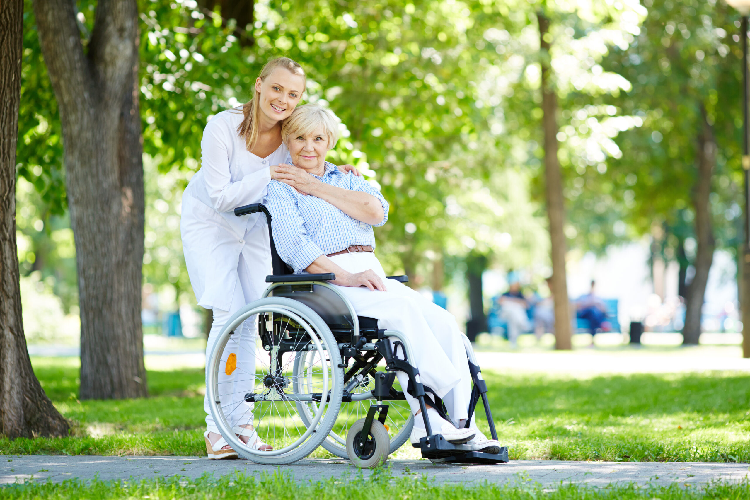 Pretty nurse taking care of senior patient in a wheelchair